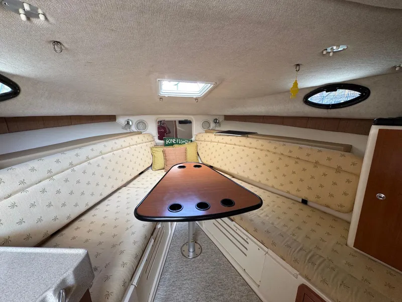 Slide: The Image of Interior of 2005 Wellcraft 290 Coastal boat with cushioned seating and wooden table. - 21