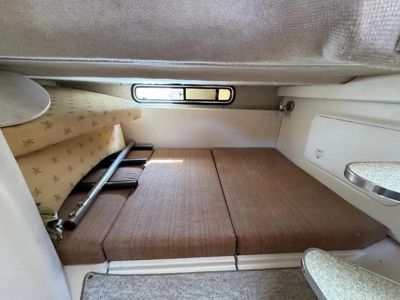 Slide: The Image of 2005 Wellcraft 290 Coastal cabin interior with cushioned seating and small window. - 24