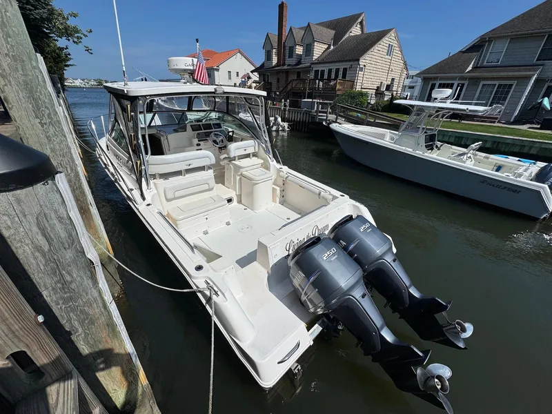 Slide: The Image of 2005 Wellcraft 290 Coastal boat docked, featuring dual outboard engines, in a residential canal setting. - 4