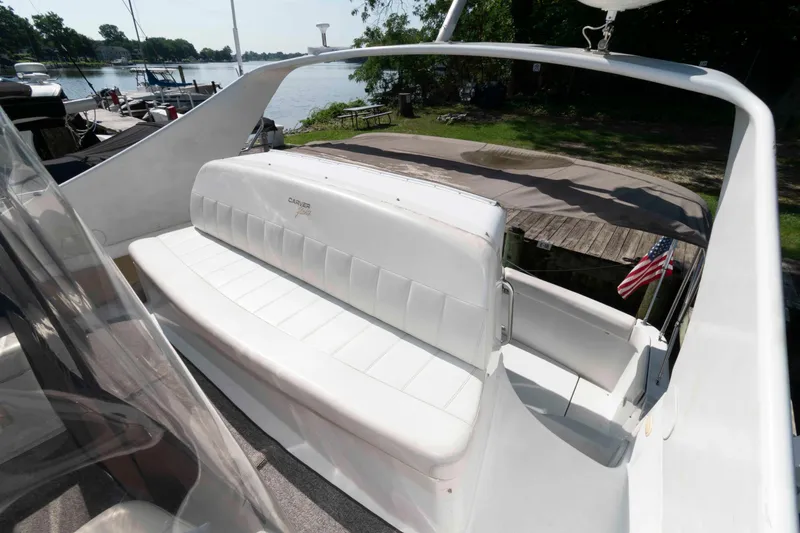 Slide: The Image of 1997 Carver 350 Mariner boat with white seating, docked by a scenic lakeside. - 8