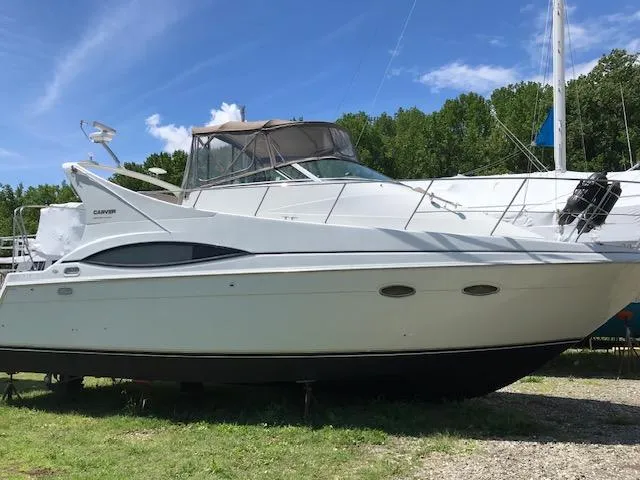 Slide: The Image of 1997 Carver 350 Mariner yacht on land, clear sky, lush trees in background. - 13