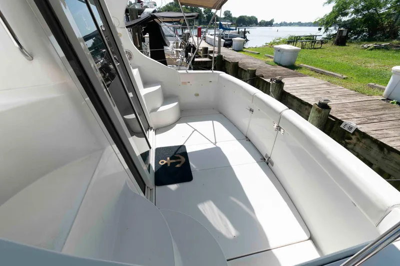 Slide: The Image of 1997 Carver 350 Mariner boat deck with seating, docked by a scenic waterfront. - 5