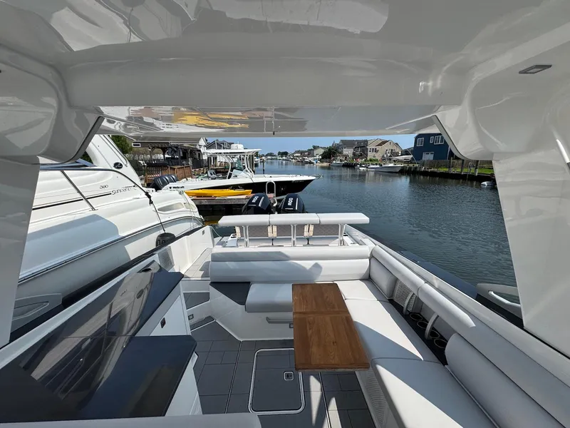 Slide: The Image of 2023 Aviara AV32 OB luxury boat interior with seating and table, docked in a scenic marina. - 18