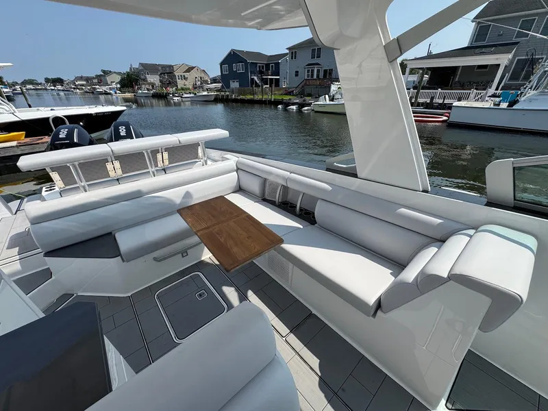 Slide: The Image of Luxurious 2023 Aviara AV32 OB boat interior with sleek seating and wooden table, docked by waterfront homes. - 21