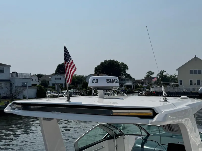 Slide: The Image of 2023 Aviara AV32 OB boat with American flag, docked in a residential waterfront area. - 25