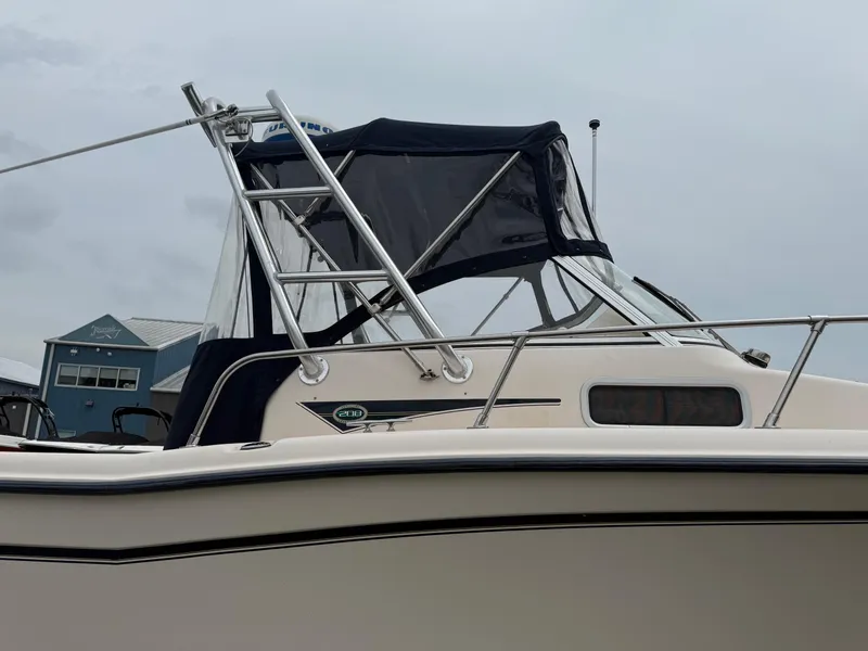 Slide: The Image of 2006 Grady-White Adventure 208WA boat with canopy, docked near a blue building. - 27