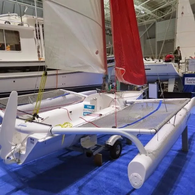 Slide: The Image of 2014 Trimaran SeaRail 19 sailboat with red and white sails displayed indoors. - 12