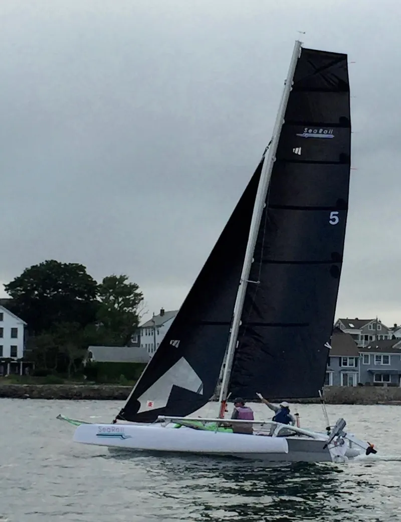 Slide: The Image of Trimaran SeaRail 19 sailing near shoreline, 2014 model, with black sails and calm waters. - 3