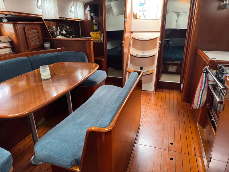 Slide: The Image of Interior of 1997 Beneteau Oceanis 461 sailboat with wooden dining area and cozy seating. - 17