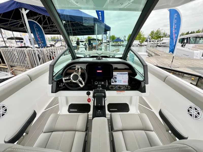 Slide: The Image of 2025 Monterey Elite 30 OB boat interior with modern dashboard and steering wheel at marina. - 6