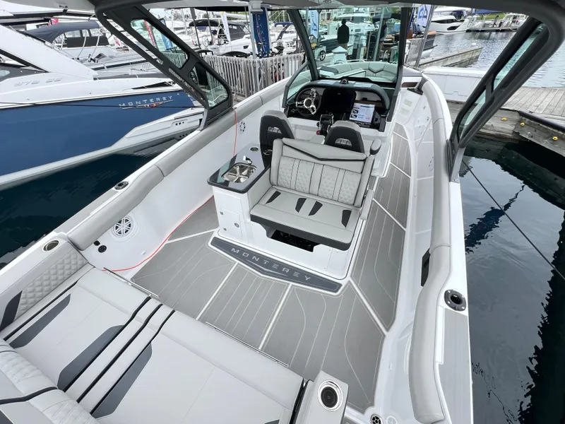 Slide: The Image of 2025 Monterey Elite 30 OB boat interior with modern seating and sleek design at a marina. - 7