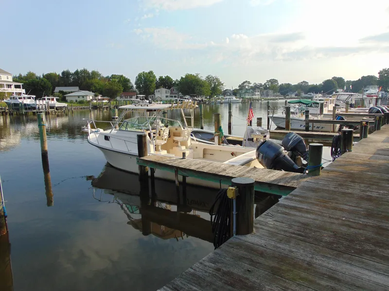 The Image of 2004 Parker Walkaround boat docked at a serene marina with calm waters. - 0