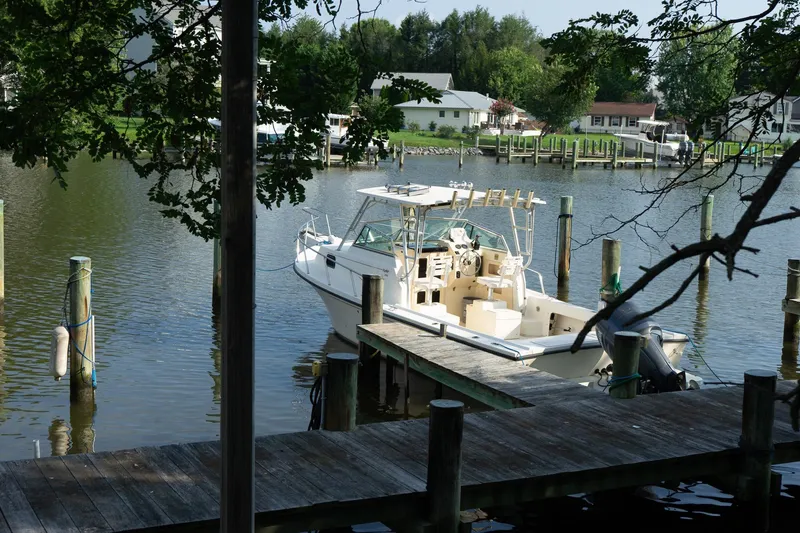 Slide: The Image of 2004 Parker Walkaround boat docked on a serene waterfront with lush greenery. - 19