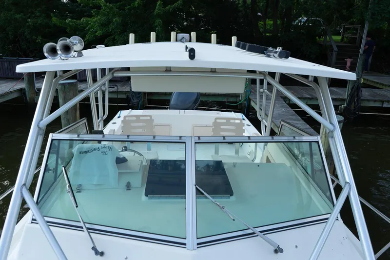 Slide: The Image of 2004 Parker Walkaround boat docked, featuring a spacious deck and windshield. - 26