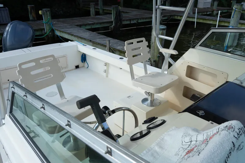 Slide: The Image of 2004 Parker Walkaround boat interior with seating and steering wheel, docked by wooden piers. - 30