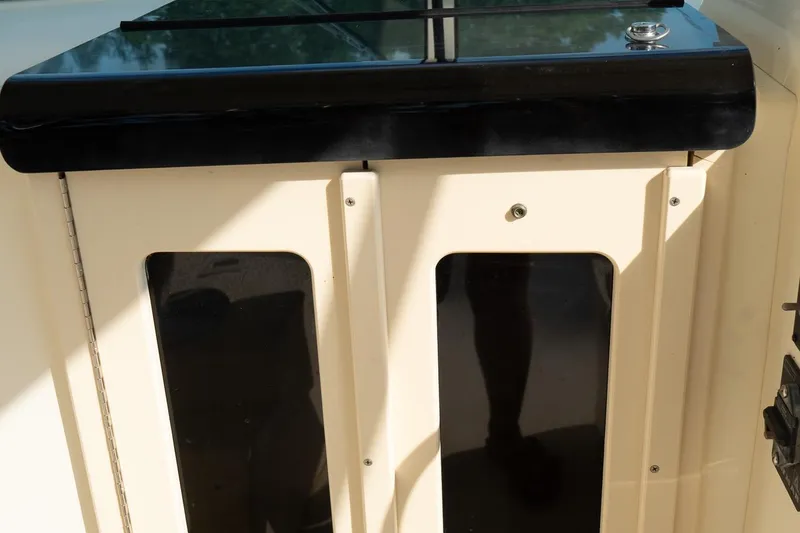 Slide: The Image of 2004 Parker Walkaround boat cabin door with black trim and sunlight reflections. - 36
