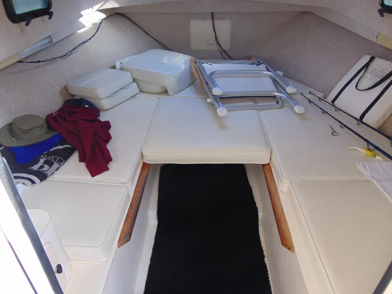 Slide: The Image of 2004 Parker Walkaround boat cabin with white cushions, fishing rods, and folded ladder. - 6