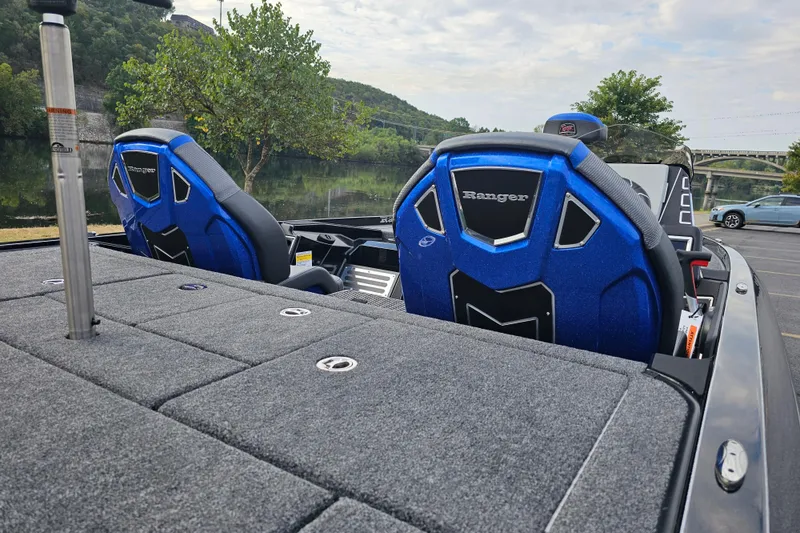 Slide: The Image of 2025 Ranger Z519R Cup-Equipped boat with blue seats, parked near a scenic river. - 2