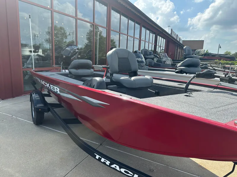 Slide: The Image of 2025 Tracker Panfish 17 boat in red, parked outside a showroom under a blue sky. - 2