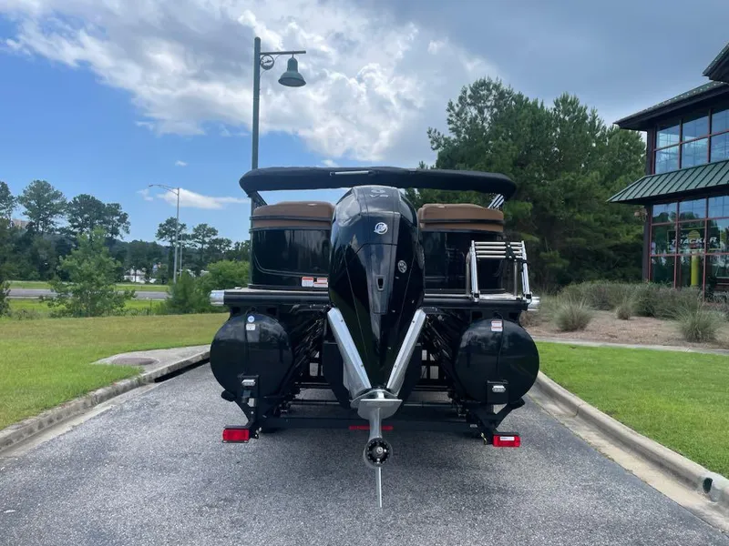 Slide: The Image of 2025 Regency 230 LE3 pontoon boat, rear view, parked outdoors on a sunny day. - 2