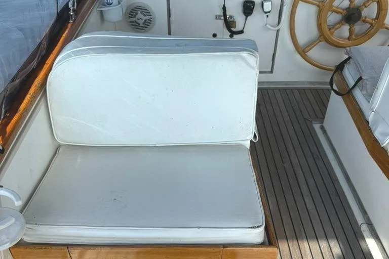 Slide: The Image of 1981 Grand Banks 36 Classic boat interior with white cushioned seating and wooden steering wheel. - 10