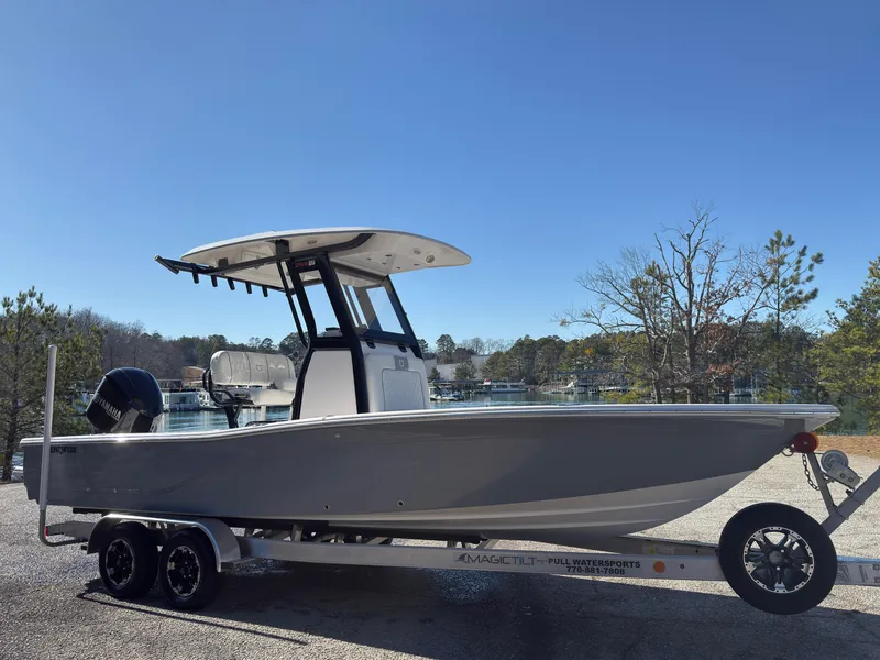 Slide: The Image of 2024 Sea Fox 251 Bay Fox boat on trailer, parked near a lake under clear blue sky. - 2