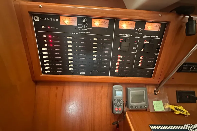 Slide: The Image of Electrical control panel on a 2002 Hunter 410 sailboat, featuring various switches and meters. - 24