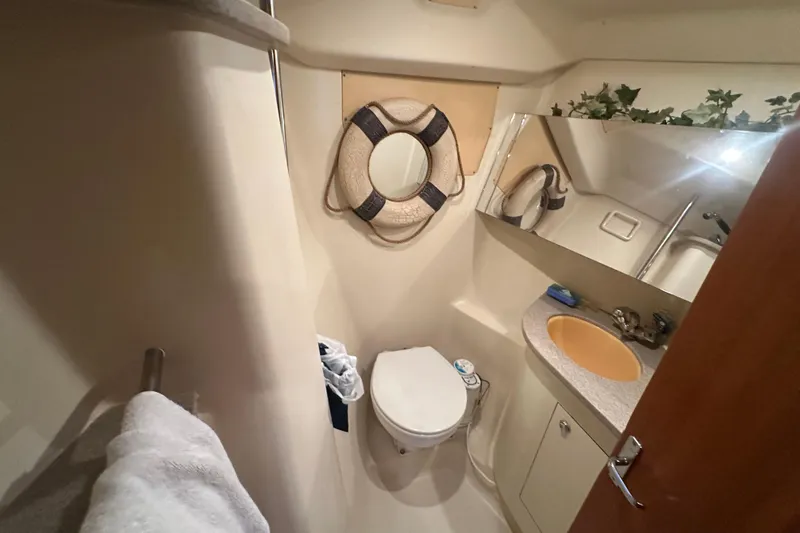 Slide: The Image of Compact bathroom in a 2002 Hunter 410 yacht, featuring a toilet, sink, and mirror. - 31