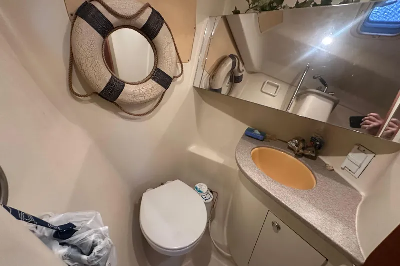 Slide: The Image of Compact bathroom in a 2002 Hunter 410 boat with a sink, toilet, and mirror. - 32