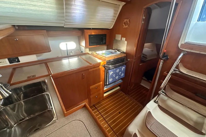 Slide: The Image of 2002 Hunter 410 yacht interior with kitchen, sink, and wooden cabinetry. - 37