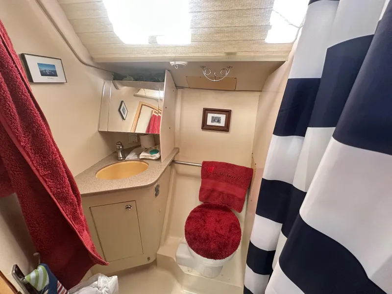 Slide: The Image of Compact bathroom in 2002 Hunter 410 boat with red accents and striped shower curtain. - 40