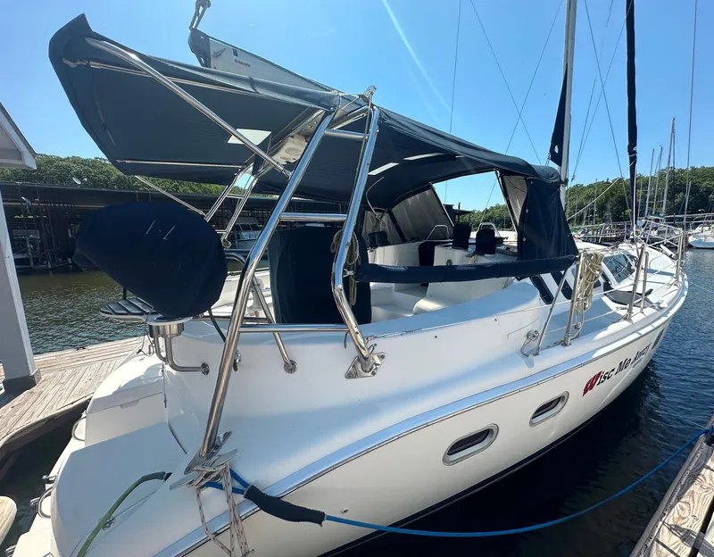 Slide: The Image of 2002 Hunter 410 sailboat docked, featuring a blue canopy and sleek white hull. - 5