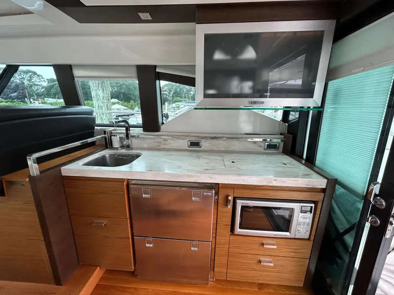 Slide: The Image of 2015 Tiara Yachts C44 Coupe interior kitchen with sink, microwave, and TV. - 9