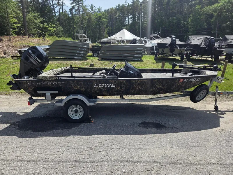 Slide: The Image of 2018 Lowe 175 Stinger boat on trailer, camo design, parked outdoors. - 1