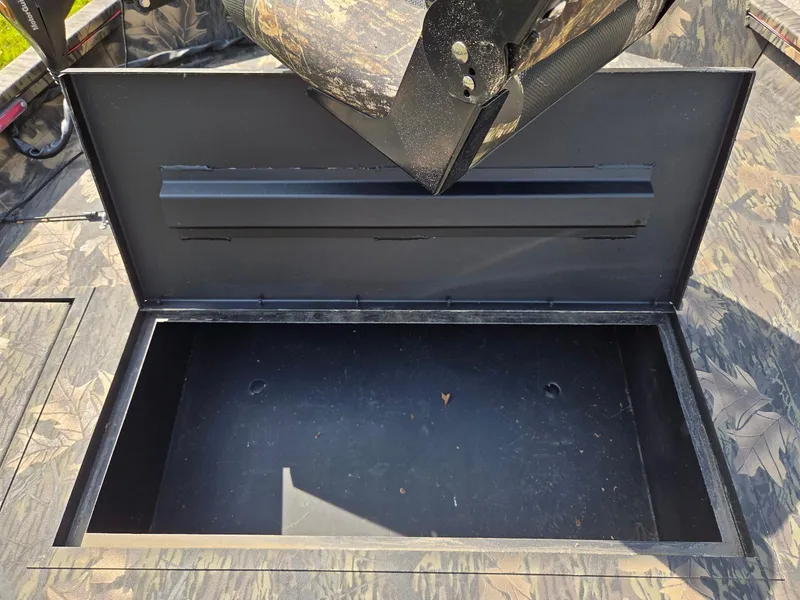 Slide: The Image of Open storage compartment on a 2018 Lowe 175 Stinger boat, featuring camouflage design. - 14