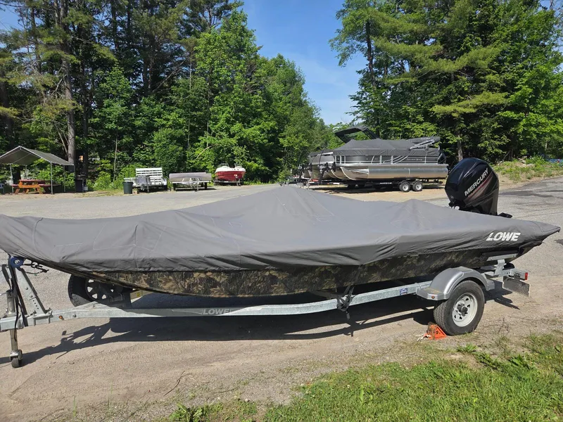 Slide: The Image of 2018 Lowe 175 Stinger boat covered, parked on trailer in wooded area. - 18