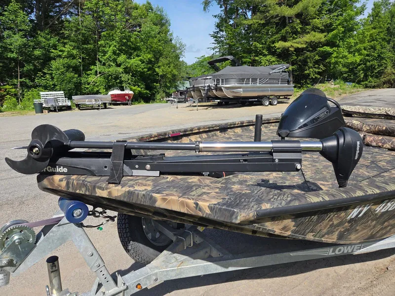 Slide: The Image of 2018 Lowe 175 Stinger boat with camo design and trolling motor, parked outdoors. - 8