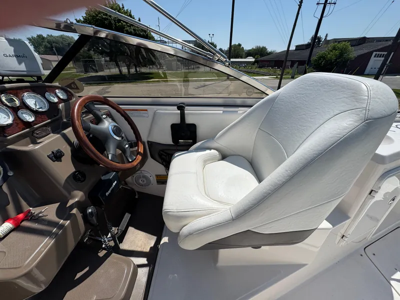 Slide: The Image of 2006 Regal 2565 Window Express boat cockpit with steering wheel and white captain's chair. - 12