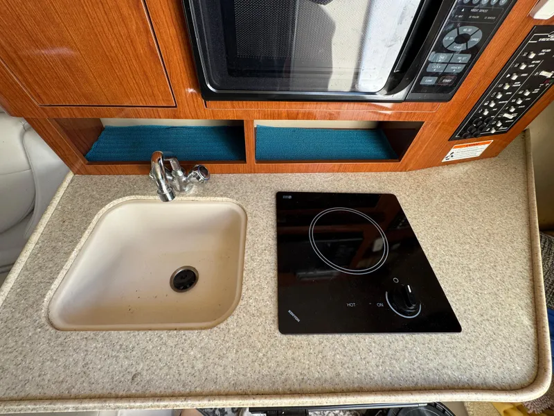 Slide: The Image of 2006 Regal 2565 Window Express boat kitchen with sink, stove, and microwave. - 22
