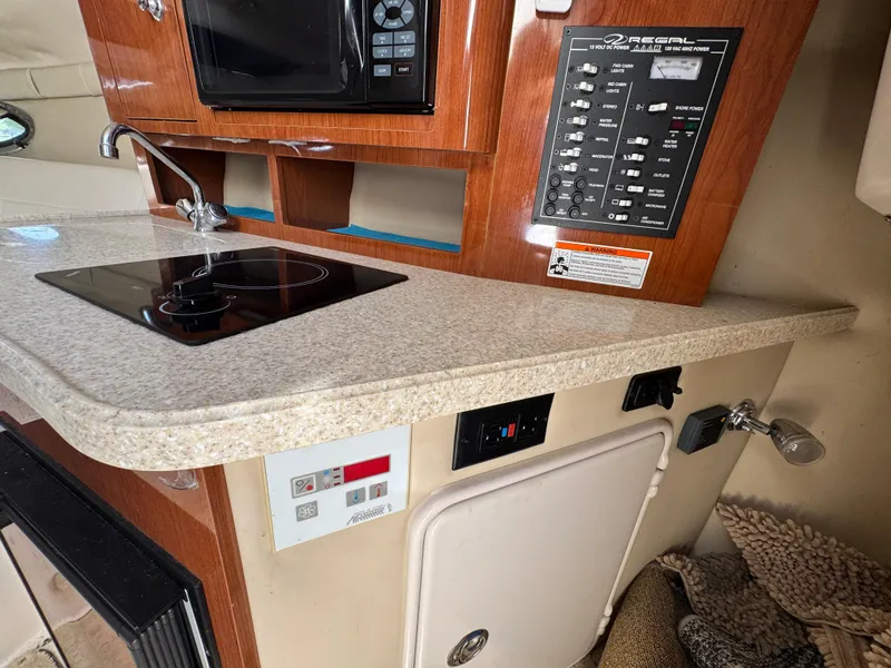 Slide: The Image of 2006 Regal 2565 Window Express boat interior with kitchenette, control panel, and modern amenities. - 25