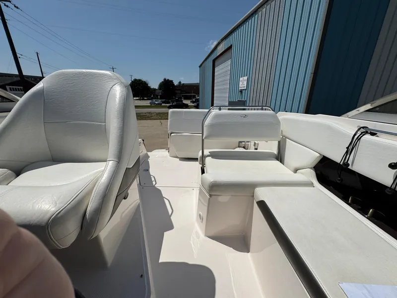 Slide: The Image of 2006 Regal 2565 Window Express boat interior with white seating and blue building background. - 7