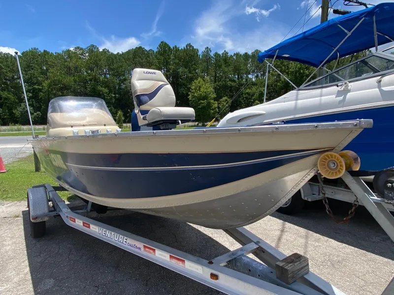 The Image of 2001 Lowe FM165S boat on trailer, parked outdoors under clear blue sky. - 1