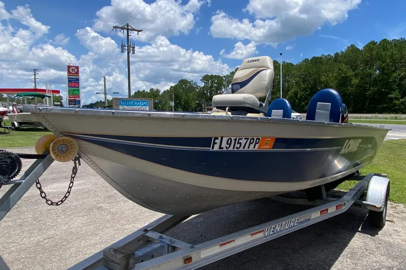 Slide: The Image of 2001 Lowe FM165S boat on trailer, parked near gas station under blue sky. - 4