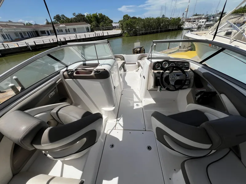 Slide: The Image of 2012 Yamaha Boats 242 Limited interior with dual seating and steering wheel, docked by the water. - 12