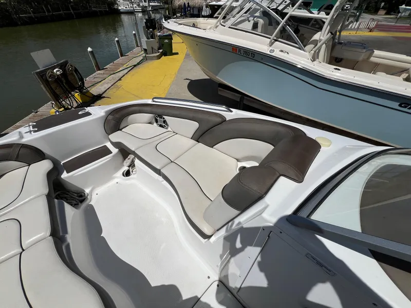 Slide: The Image of 2012 Yamaha Boats 242 Limited interior with cushioned seating at a dock. - 7
