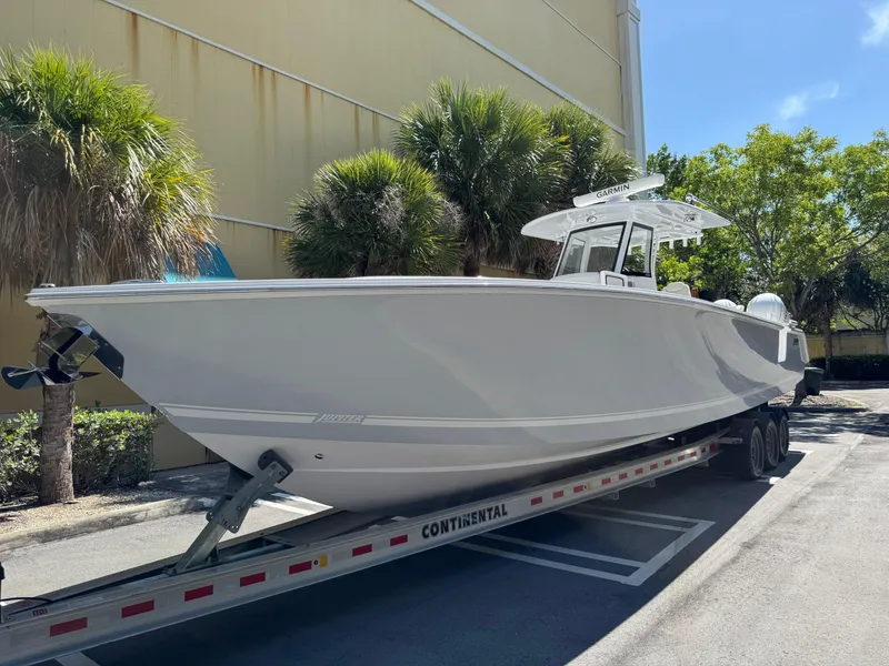 The Image of 2025 Jupiter 380LS boat on trailer, parked outdoors near palm trees. - 0