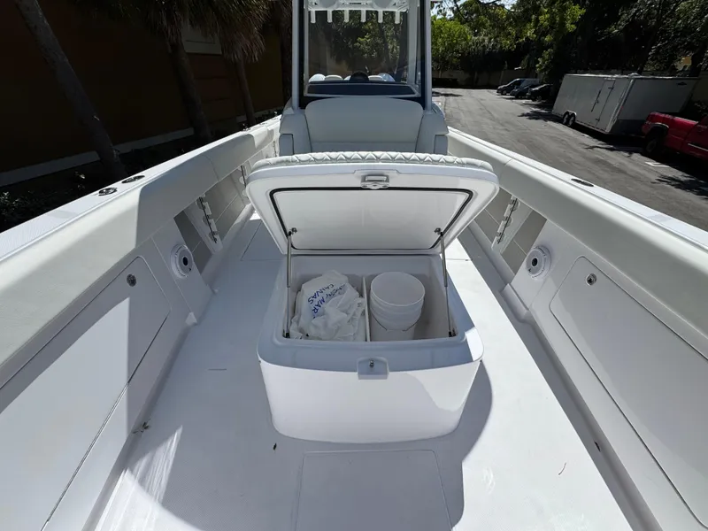 Slide: The Image of Open storage compartment on 2025 Jupiter 380LS boat, featuring a bucket and bag inside. - 10
