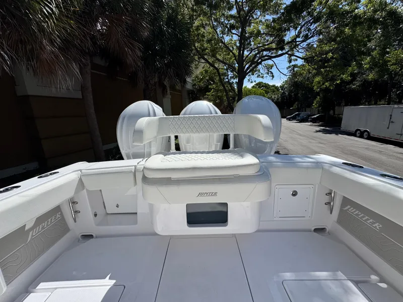 Slide: The Image of 2025 Jupiter 380LS boat interior with seating and storage, surrounded by trees. - 22