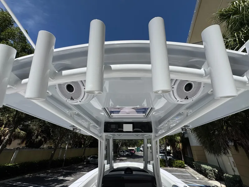 Slide: The Image of 2025 Jupiter 380LS boat roof with rod holders and speakers under clear blue sky. - 27
