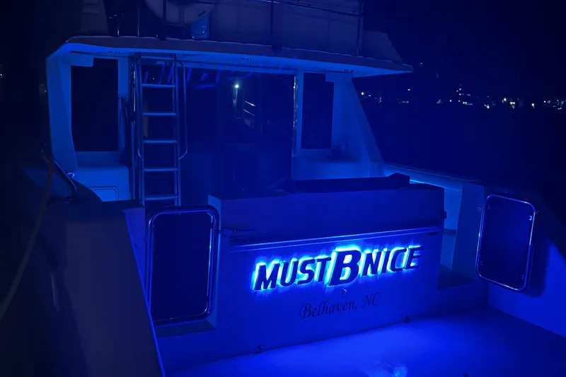 Slide: The Image of Custom Sports Catamaran 44, 2001, illuminated at night with blue lights, "Must B Nice" signage. - 2